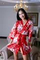 A woman in a red robe sitting on a couch.