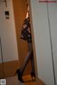 A woman in a black dress and high heels standing in a bathroom.