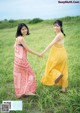 A couple of women holding hands in a field.