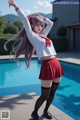 A woman in a school uniform standing next to a swimming pool.