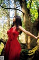 A woman in a red dress standing on a tree branch.