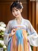 A woman wearing a colorful hanbok standing in front of a window.