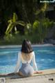 A woman sitting on the edge of a swimming pool.