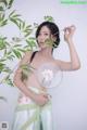 A woman in a green dress holding a fan.
