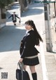 A woman in a school uniform is walking down the street.