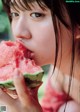 A young woman eating a slice of watermelon.