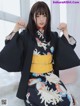 A woman in a black kimono sitting on a white rug.