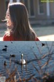 A woman in a red shirt is looking at ducks in the water.